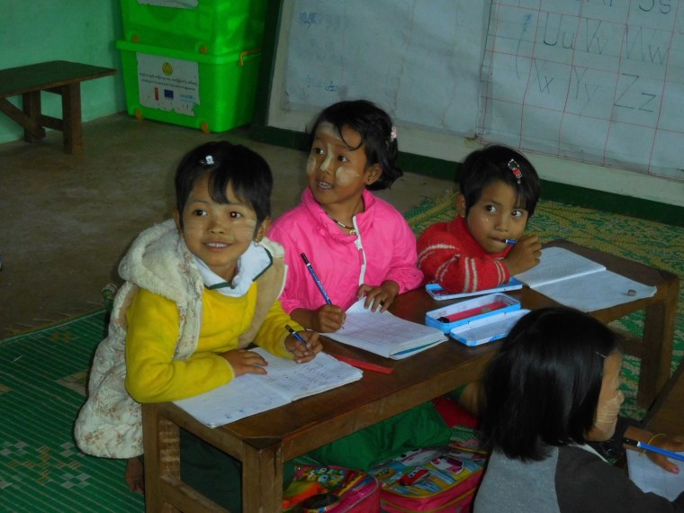 3 Kinder sitzen in einer burmesischen Schulbank